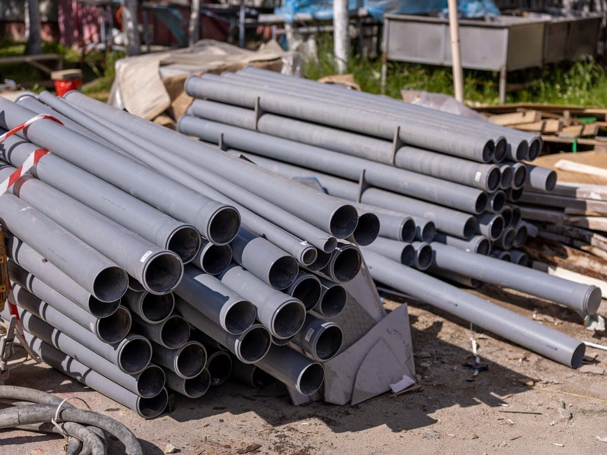 Bundled lengths of grey PVC conduit staged on site before installation.