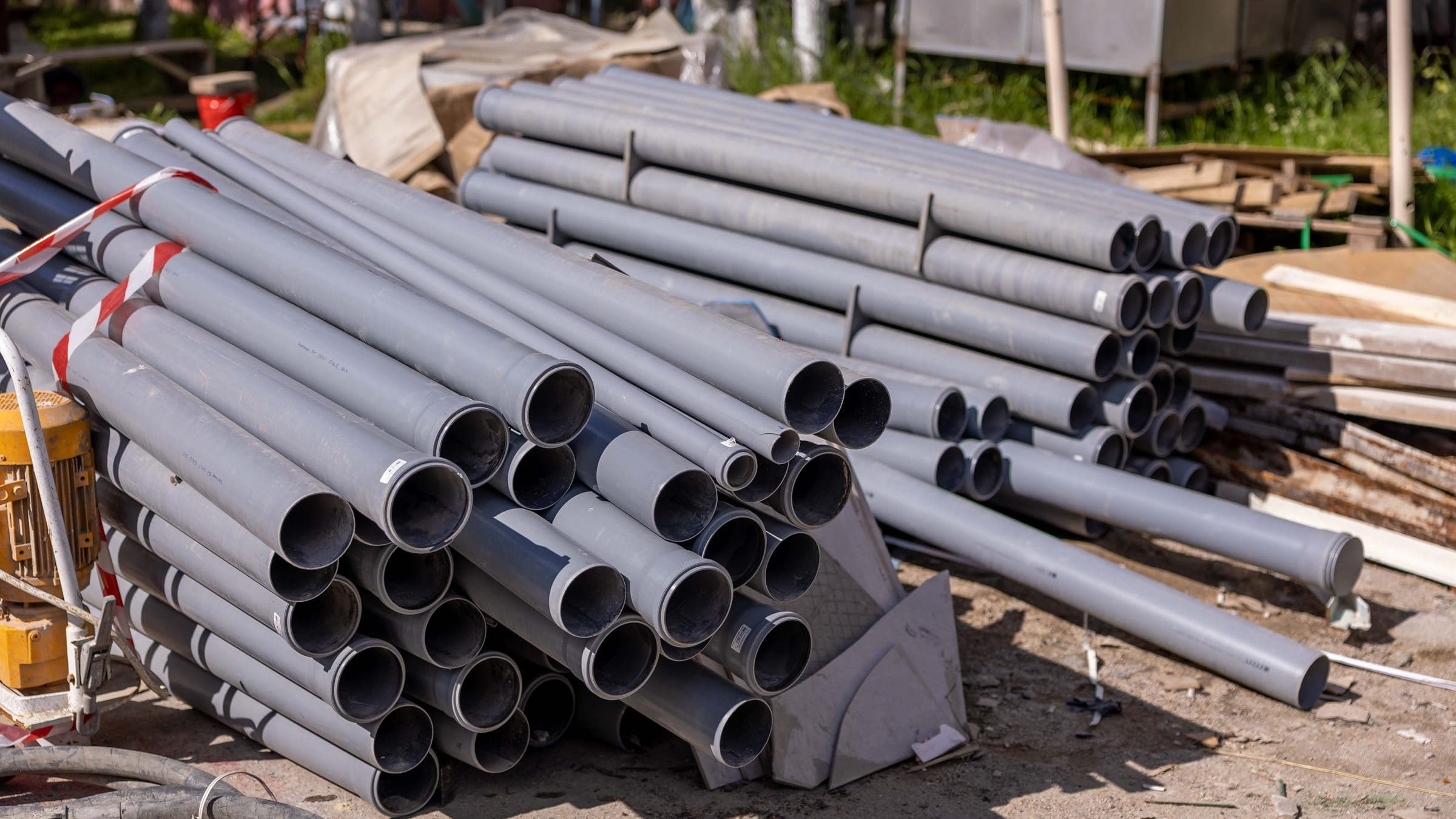 Bundled lengths of grey PVC conduit staged on site before installation.